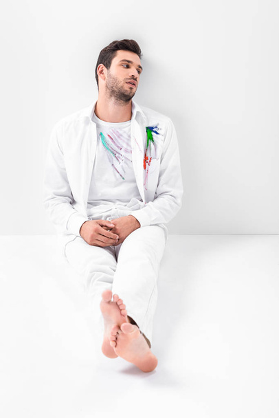 adult barefoot man with painted clothes sitting on floor - Foto, Bild