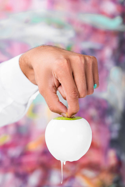 close up of male hand holding white painted apple - Foto, Bild