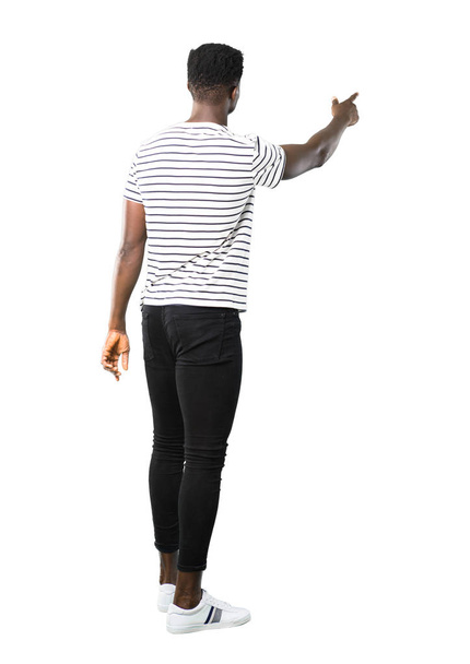 Повне тіло темношкірого чоловіка з смугастою сорочкою, спрямованою назад з індексним пальцем, що представляє продукт ззаду на білому тлі
 - Фото, зображення