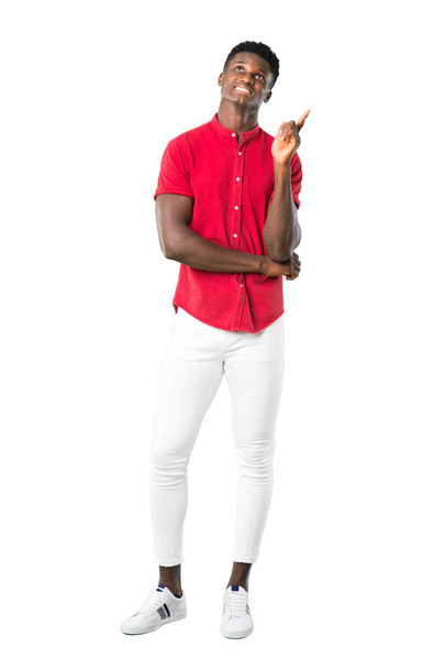 Ganzkörper junger afrikanisch-amerikanischer Mann, der mit dem Zeigefinger auf eine großartige Idee zeigt und auf weißem Hintergrund aufblickt - Foto, Bild