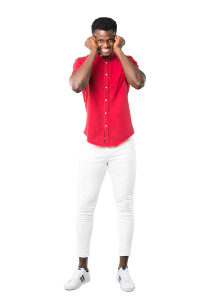 Full body of Young african american man covering both ears with hands. Frustrated expression on white background - Fotó, kép