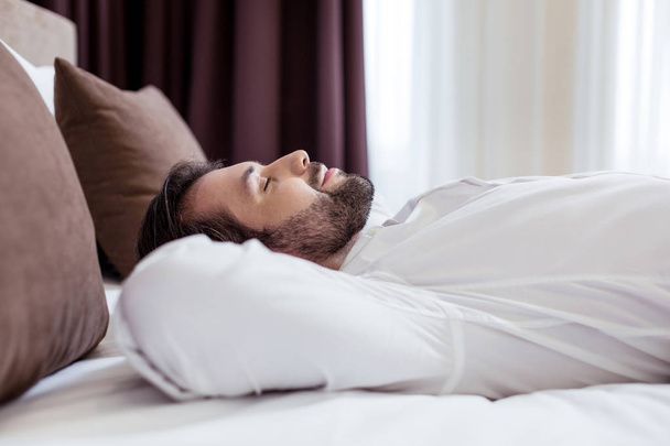 Homem agradável alegre deitado na cama
 - Foto, Imagem