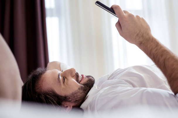 Positive handsome man looking at the smartphone screen - Photo, Image