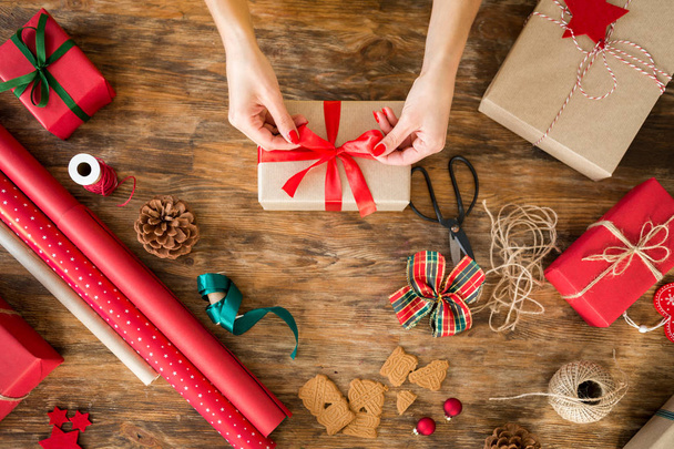 DIY Gift Wrapping. Woman wrapping beautiful christmas gifts on rustic wooden table. Overhead view of christmas wrapping station. - 写真・画像