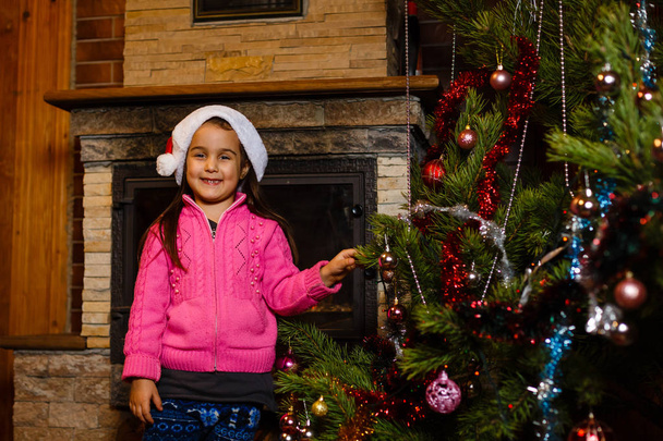 onnellinen pieni tyttö joulupukki hattu joulukuusi - Valokuva, kuva