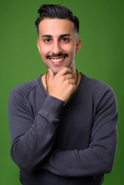 Jonge knappe Iraanse man met snor tegen groene pagina - Foto, afbeelding