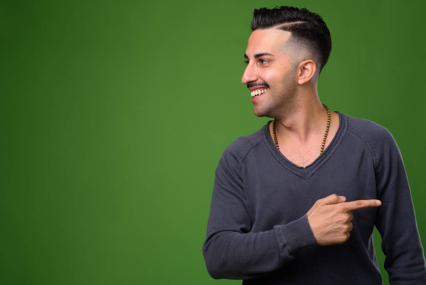 Joven hombre iraní guapo con bigote contra fondo verde
 - Foto, Imagen