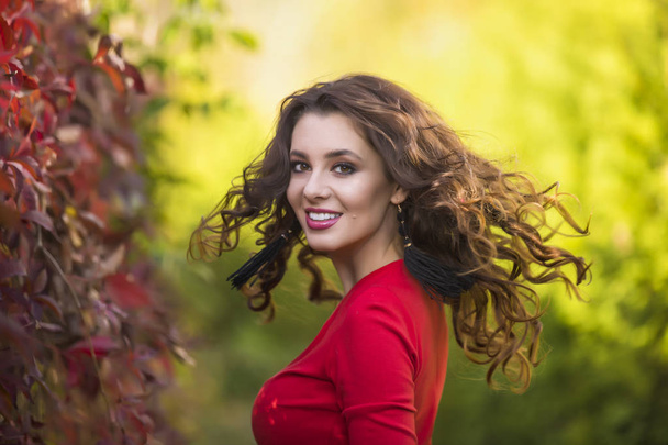 Beautiful young woman in red dress on a sunny autumn day - Valokuva, kuva