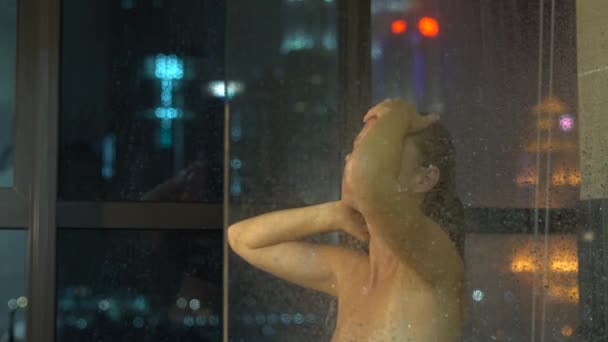 Mujer joven tomando ducha en el baño por la ventana en la noche
. - Metraje, vídeo