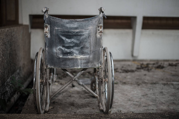 Stary wózek inwalidzki w ciemny ton z bliska. - Zdjęcie, obraz
