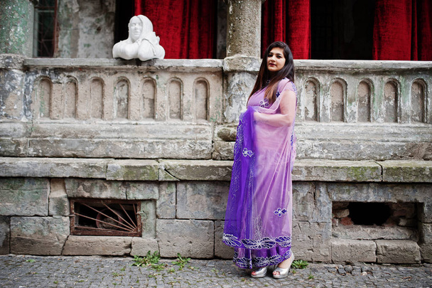 Indian hindu girl at traditional violet saree posed at  street against old house with red curtains. - Foto, imagen
