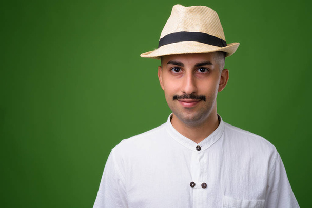 Young handsome Iranian man with mustache against green backgroun - Фото, зображення