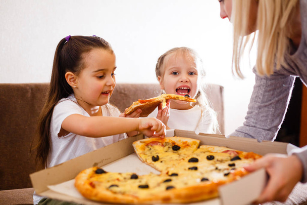 Nuori iloinen tytöt syövät pizzaa kotona
 - Valokuva, kuva