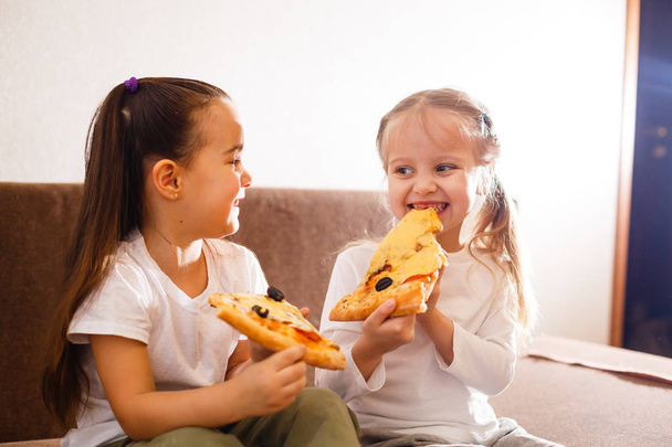 Young cheerful girls eating pizza at home - Foto, imagen