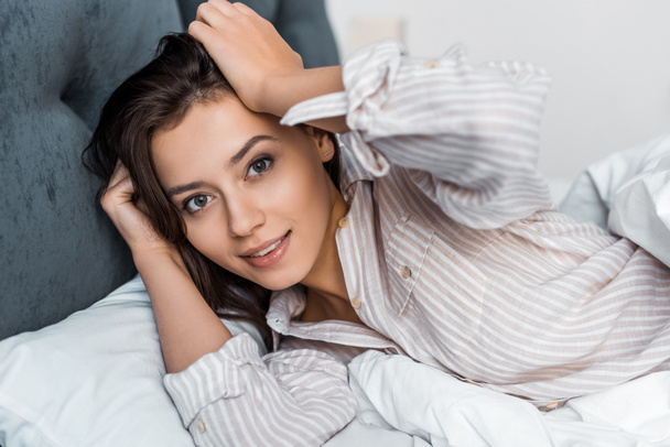 beautiful brunette girl in pajamas relaxing in bed - 写真・画像