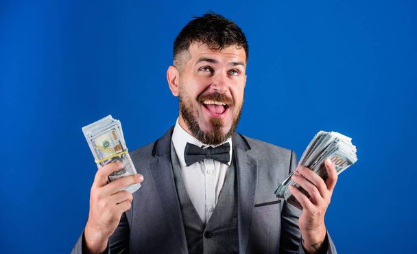 Richness and wellbeing concept. Get cash easy and quickly. Cash transaction business. Easy cash loans. Man formal suit hold pile of dollar banknotes blue background. Businessman got cash money - Foto, Imagem