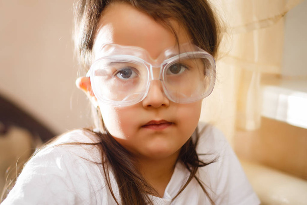 Little girl experimenting in elementary science class with protective glasses - Valokuva, kuva