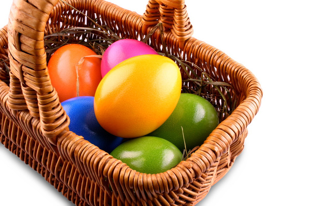 Wicker basket with colorful Easter eggs, isolated - Photo, Image