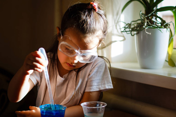 Little girl experimenting in elementary science class with protective glasses - Foto, Imagem