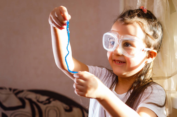 Menina experimentando na aula de ciências elementares com óculos de proteção
 - Foto, Imagem