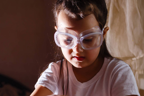 Little girl experimenting in elementary science class with protective glasses - Photo, Image
