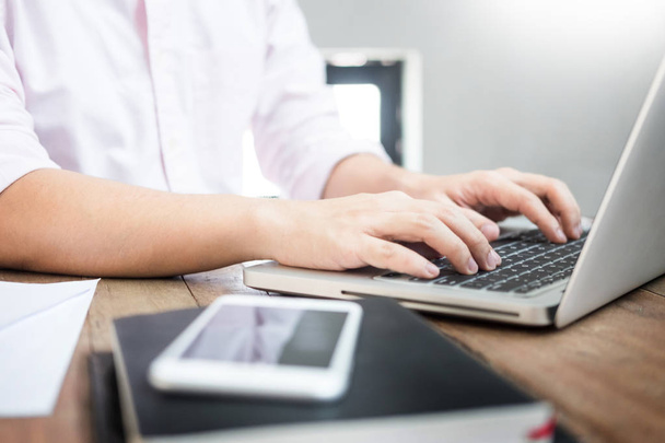 jonge Kaukasische man aan het werk thuis werk schrijven opmerking aan sommige project met zijn laptop op een bureau, strartup business, e-learning concept van plan. - Foto, afbeelding