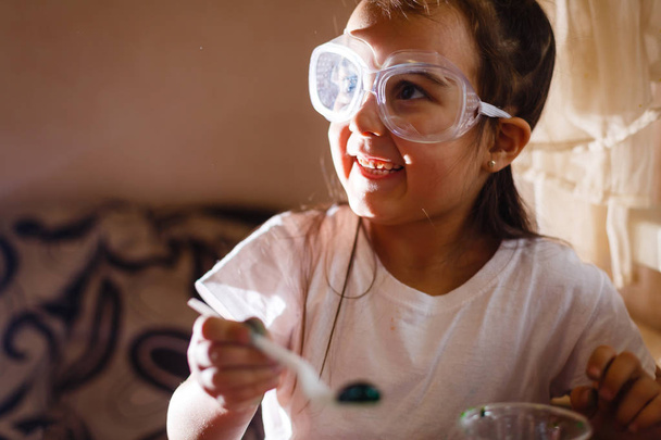 Menina experimentando na aula de ciências elementares com óculos de proteção
 - Foto, Imagem