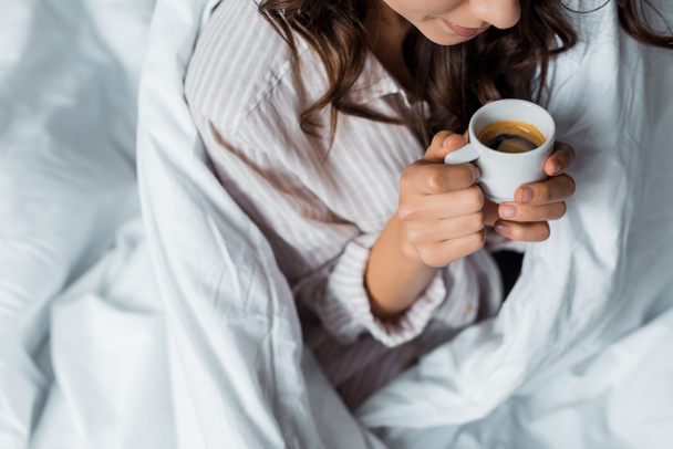 Обрезанный вид девушки, держащей чашку кофе эспрессо по утрам
 - Фото, изображение