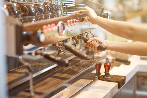 Профессиональное оборудование Хороший бариста, стоящий в кофейне во время чистки кофемашины
 - Фото, изображение