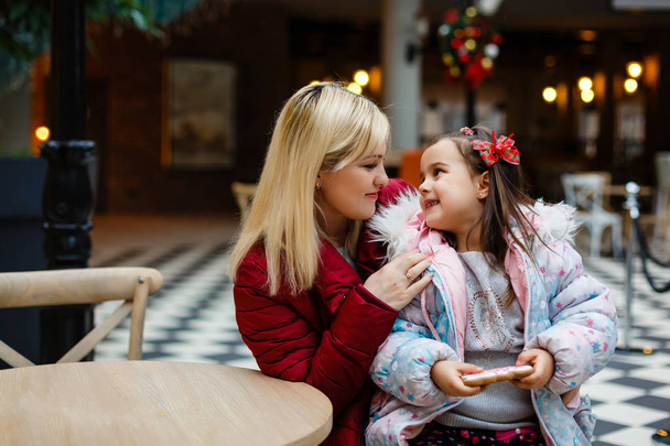 Молода мати з маленькою дочкою в різдвяному прикрашеному кафе
 - Фото, зображення