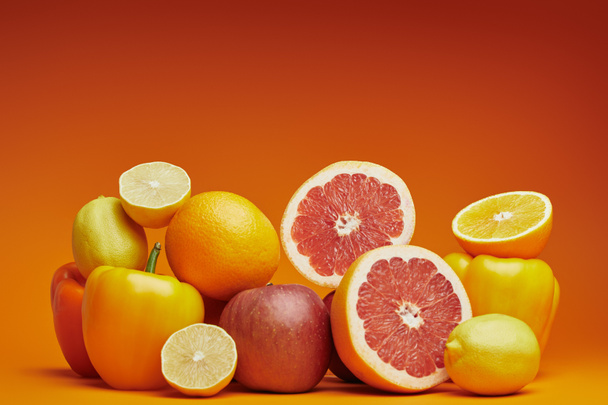 close-up view of fresh ripe citrus fruits and bell peppers on orange background  - Photo, Image