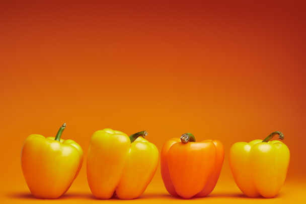 close-up view of fresh organic bell peppers on orange background   - Foto, imagen