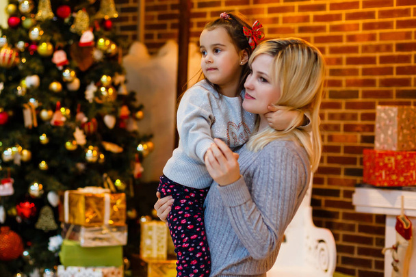 Jonge moeder met kleine dochter in kerst ingericht interieur  - Foto, afbeelding