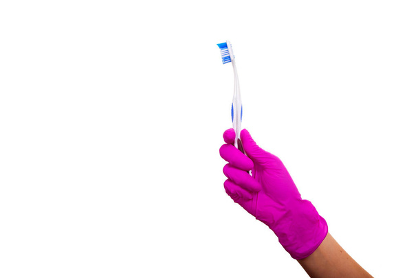 Female hands in purple medical gloves holding a toothbrush. Arms of dentist with clean brush isolated on a white background. - Foto, Bild