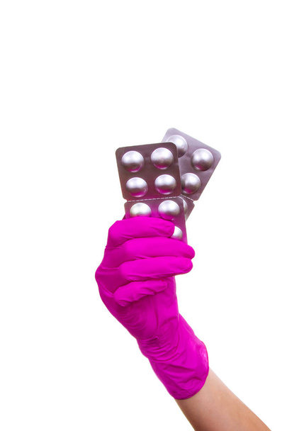 Naisilla on purppuranpunaiset hanskat pillereiden kanssa. Käsivarret, joiden lääkeannos on eristetty valkoisella pohjalla
. - Valokuva, kuva