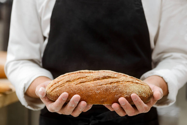 Baker holding a fresh bread - Fotoğraf, Görsel
