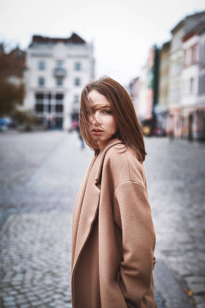 young woman in brown coat posing on the street - Fotografie, Obrázek