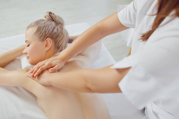 Body massage. Blond woman in spa salon doing body massage. - Valokuva, kuva
