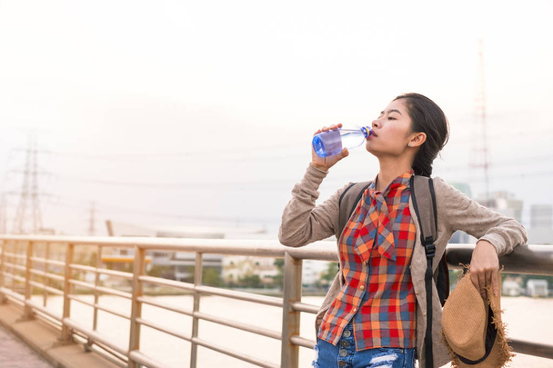 Азиатская девушка Питьевая вода Оставайтесь уставшим от жажды туристический рюкзак расслабиться время на отдыхе
. - Фото, изображение