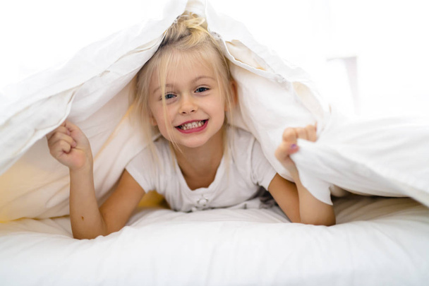 A Cheerful little girl in bed having fun - Valokuva, kuva
