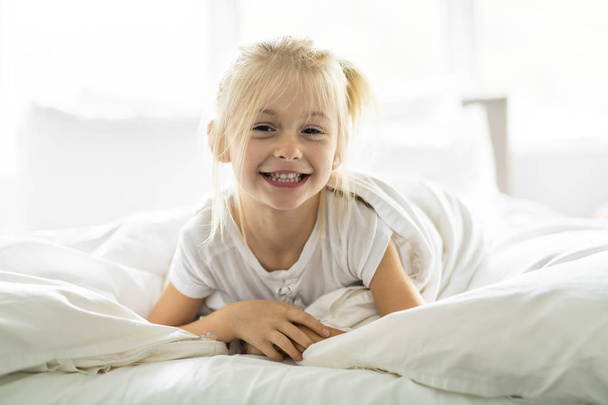 A Cheerful little girl in bed having fun - Fotoğraf, Görsel