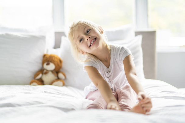 A Cheerful little girl in bed having fun - Фото, изображение