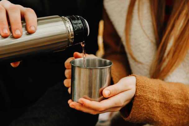 Guy pours tea in mug from thermos. Concept heat retention. - 写真・画像