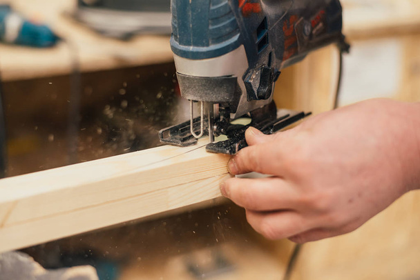 Man sanding a wood with sander in a workshop - Foto, afbeelding