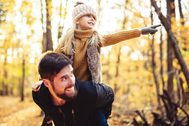 A happy father and daughter having fun in autumn park - Foto, afbeelding