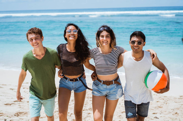 Group of cheerful young people walking together hold a ball - Foto, imagen