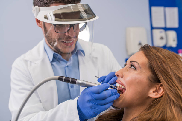 Ο οδοντίατρος εξετάζει τα δόντια του ασθενούς στο οδοντιατρείο - Φωτογραφία, εικόνα
