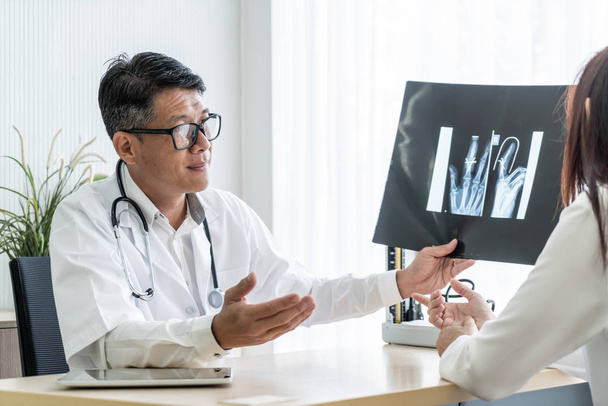 Médico asiático e paciente estão discutindo com filme de raios X no escritório
 - Foto, Imagem