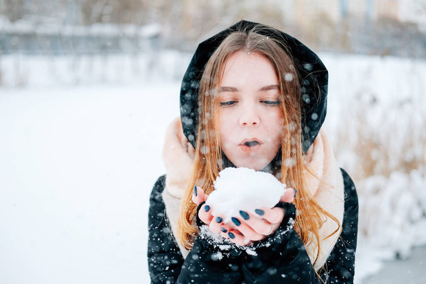 Atraktivní blondýna mladá dospělých žena baví s prvním sněhem nosí ležérní oblečení černou bundu, džíny, růžové kožené boty, batoh a béžový šátek - Fotografie, Obrázek