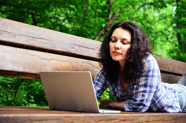 Путешествующая женщина использует ноутбук в парке. Концепция внештатной работы в путешествиях, работающих на природе
 - Фото, изображение